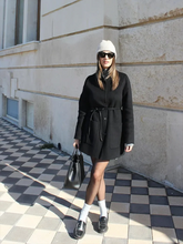 a lady wears a black wool coat with black loafers